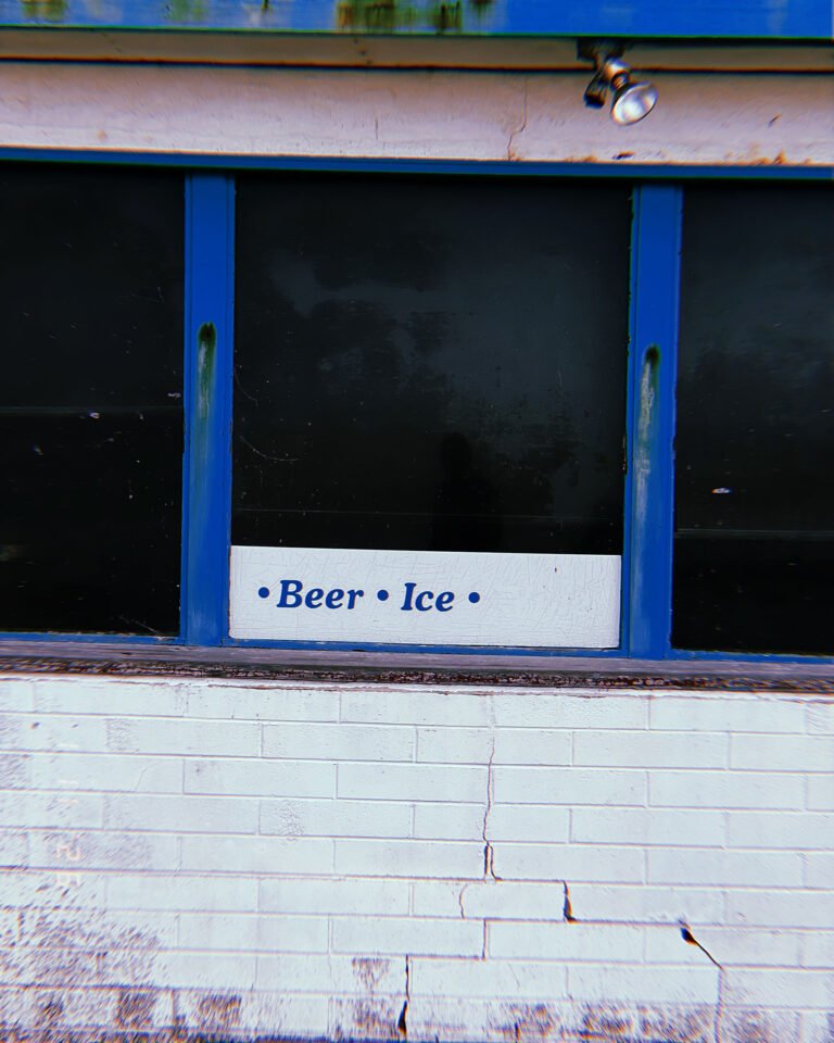 storefront window with sign reading Beer Ice on cracked white brick wall in San Francisco