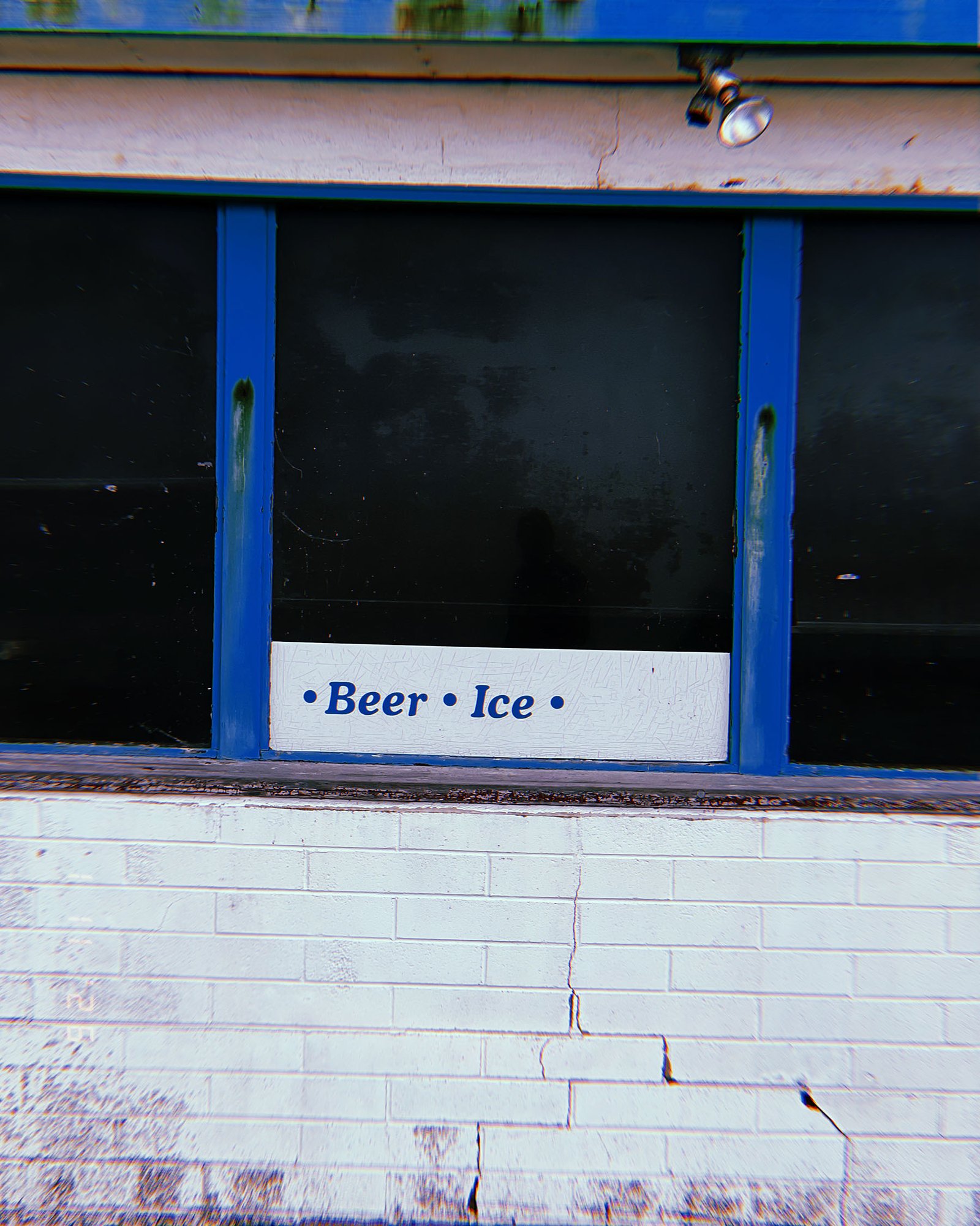 storefront window with sign reading Beer Ice on cracked white brick wall in San Francisco