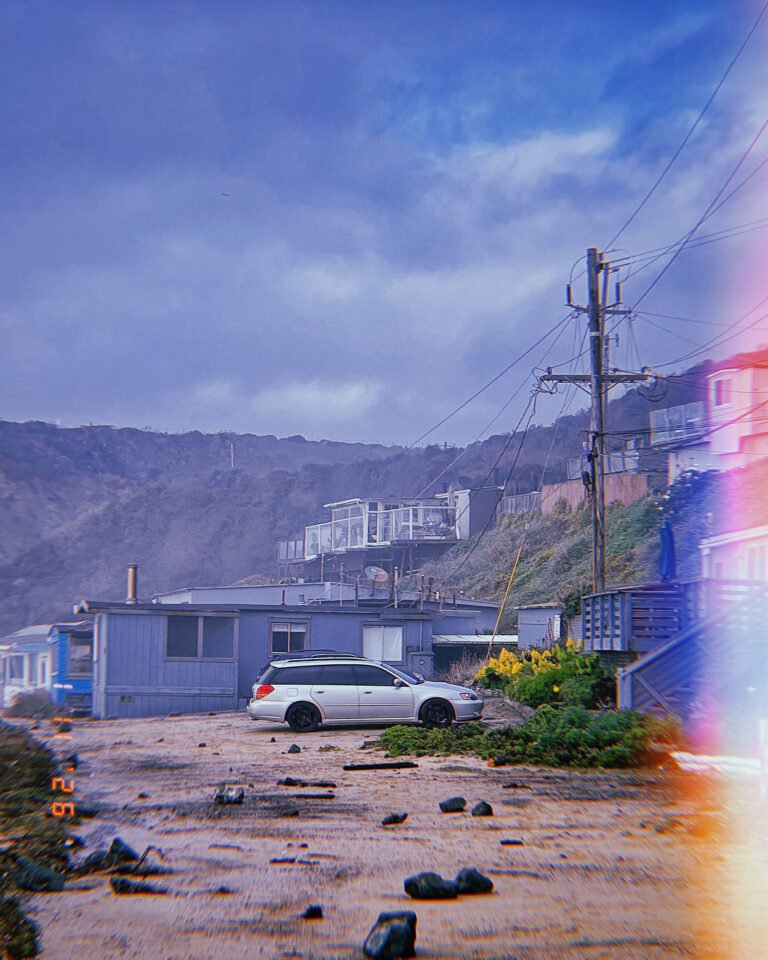 coastal houses and parked white car after storm with debris on ground in San Francisco