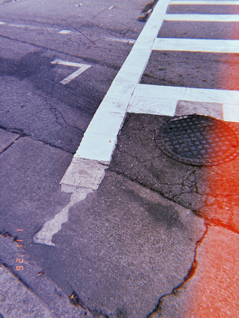 street corner with crosswalk lines, cracked asphalt and manhole cover in San Francisco