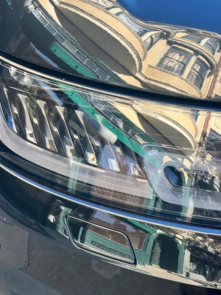 reflection of ornate building facade in car headlight and hood