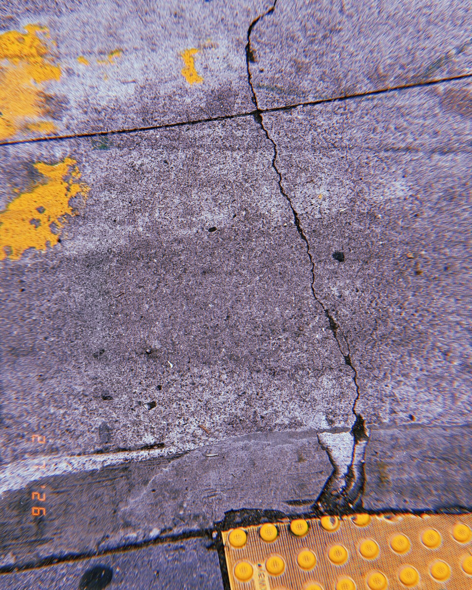 cracked concrete sidewalk with fragments of faded yellow paint markings