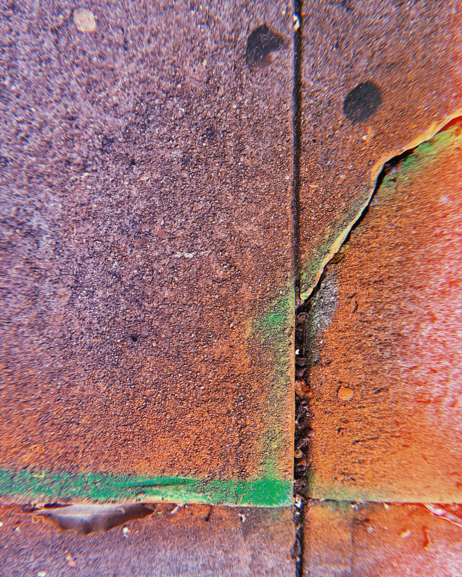 faded green utility spray paint remaining along a cracked sidewalk joint