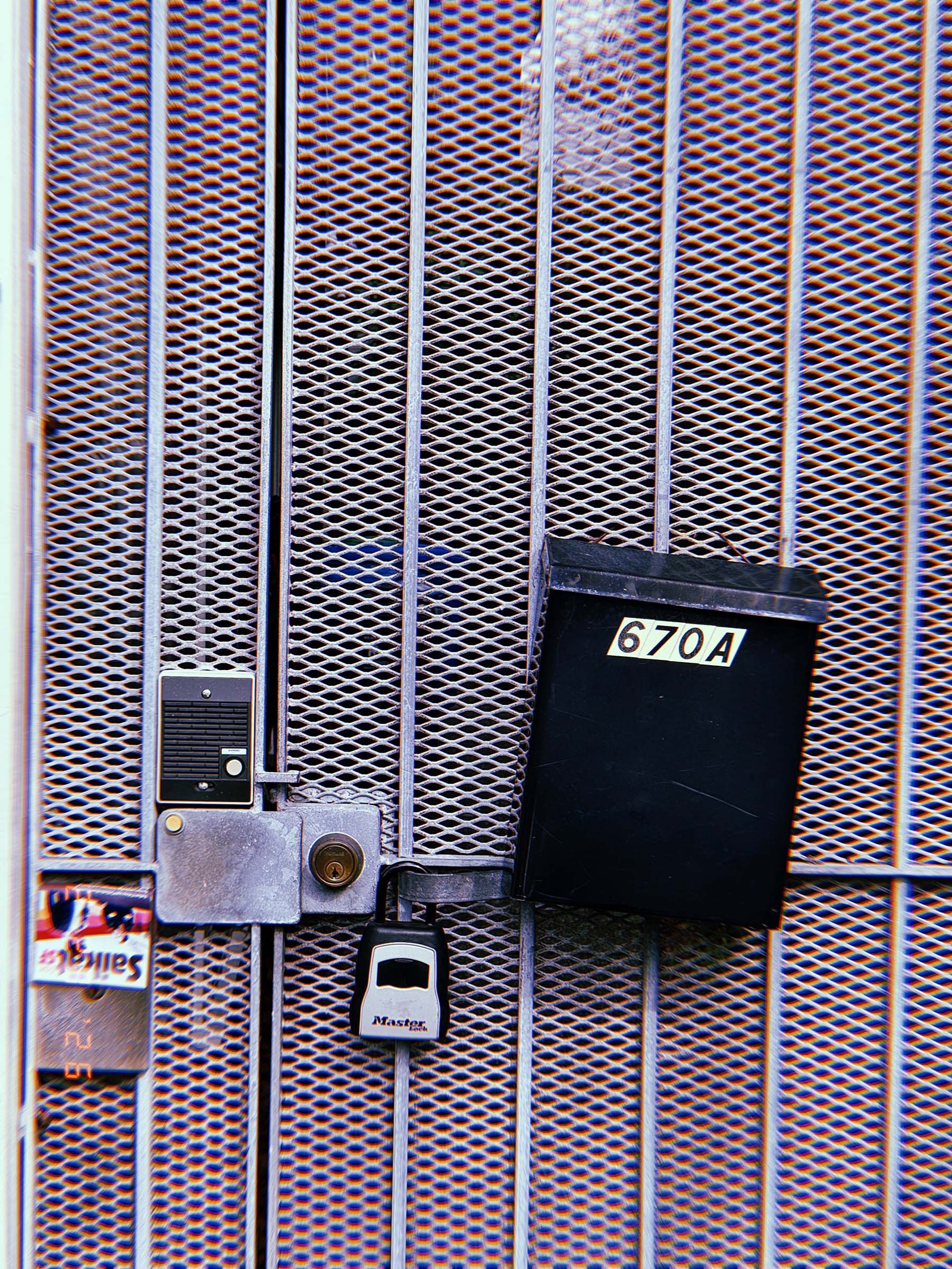 metal security gate with intercom button, lock mechanism, and address mailbox