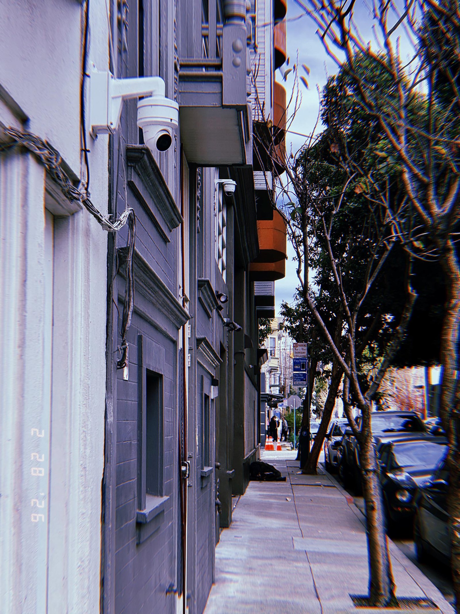 multiple surveillance cameras mounted along residential building facade overlooking sidewalk