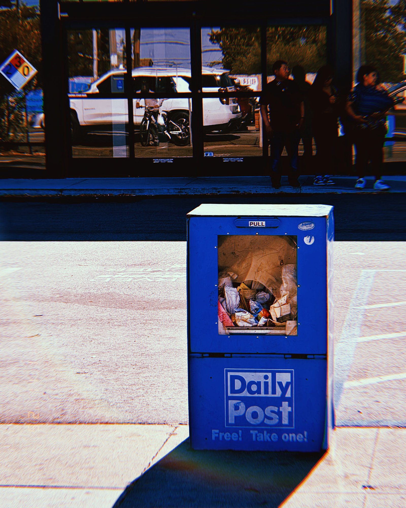 blue Daily Post newspaper box filled with trash on sidewalk in San Francisco