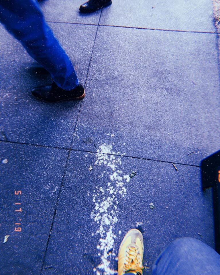 white splatter marks across concrete sidewalk with pedestrians walking past