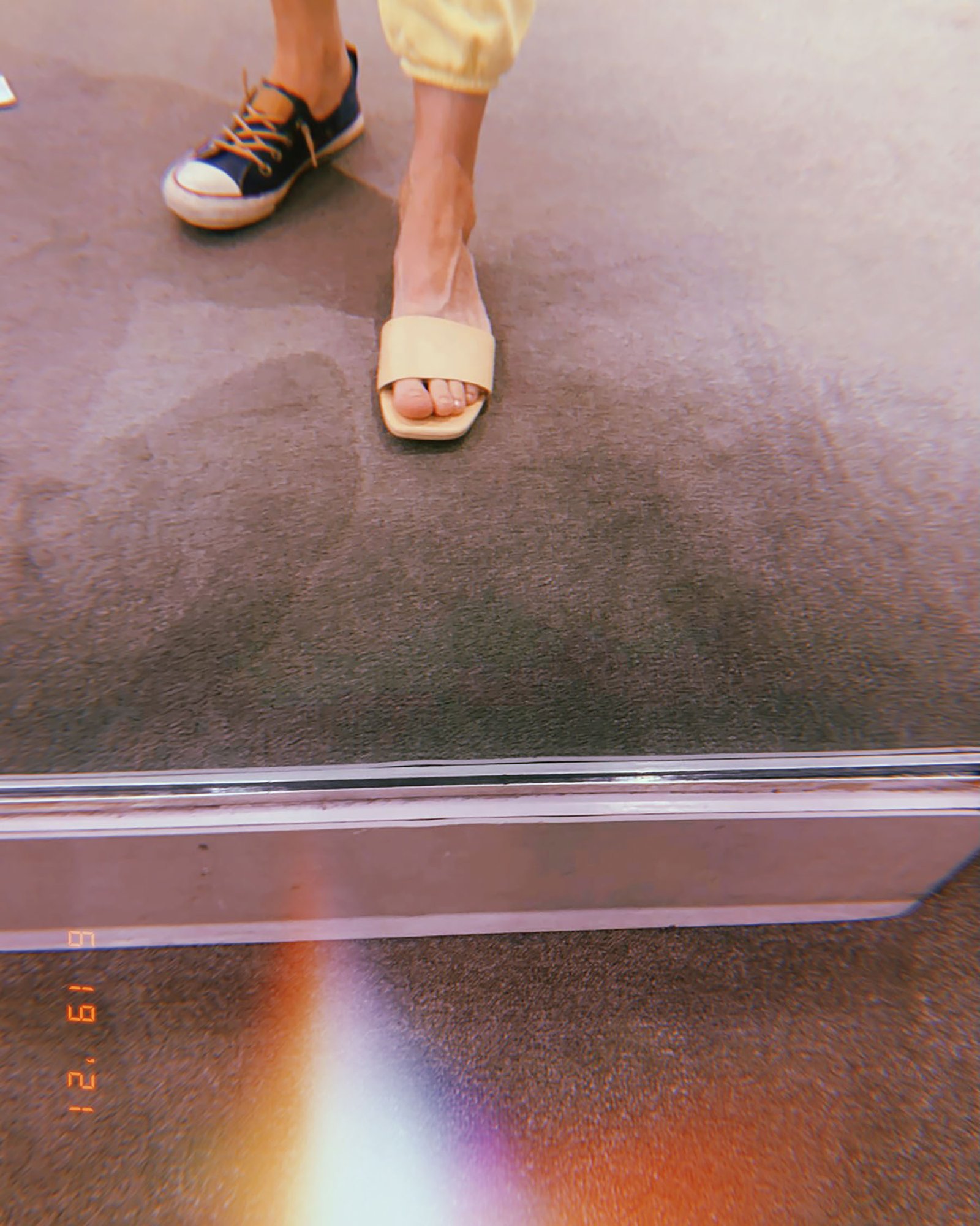 two different shoes stepping across metal threshold and textured pavement