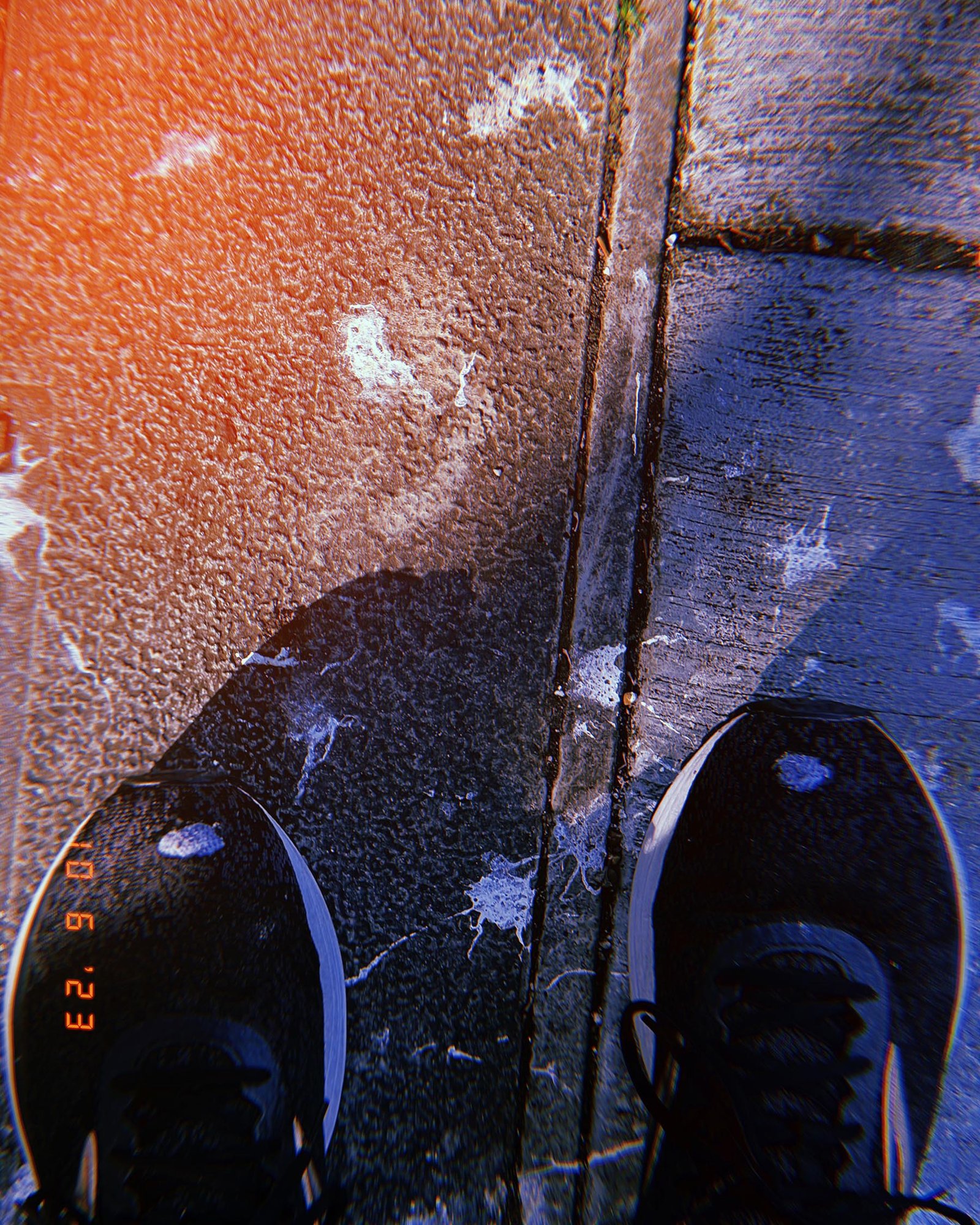 shoes standing on asphalt and sidewalk seam with marks and stains on street surface