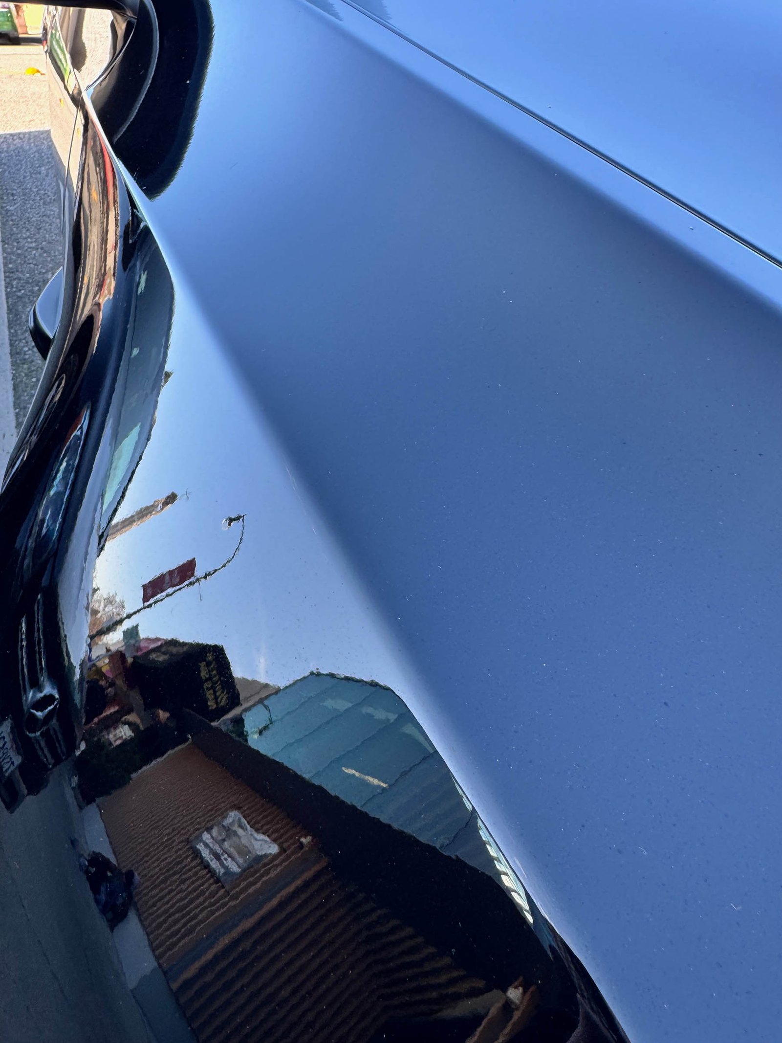 buildings and street sign reflected in dark blue car body