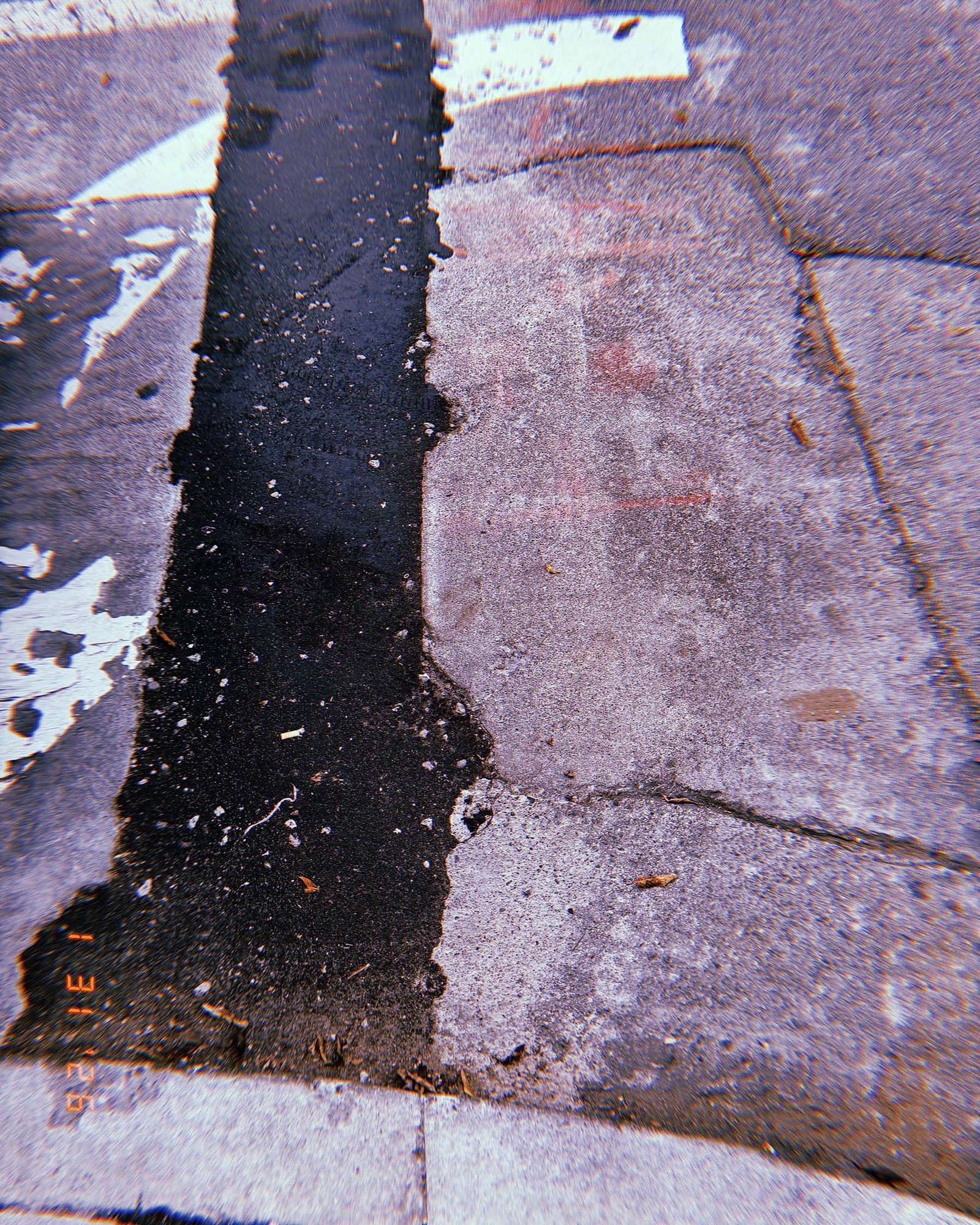 strip of dark asphalt repair cutting through older concrete sidewalk slabs