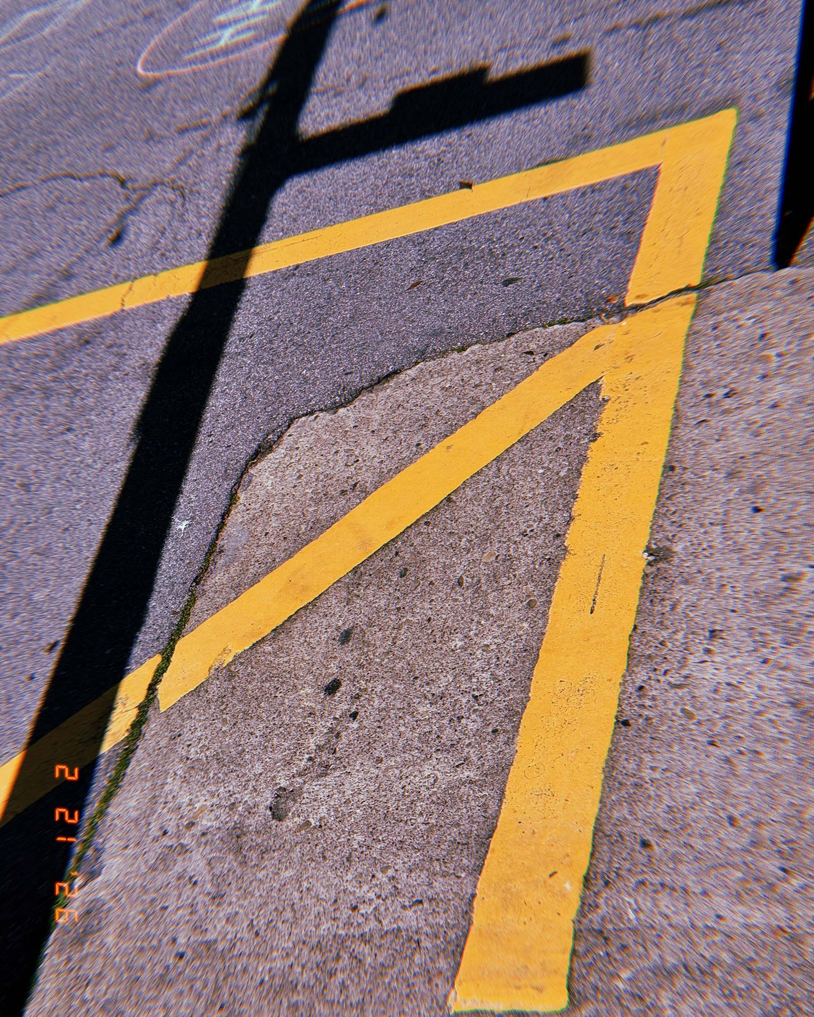 faded yellow street boundary lines surrounding a patched section of asphalt