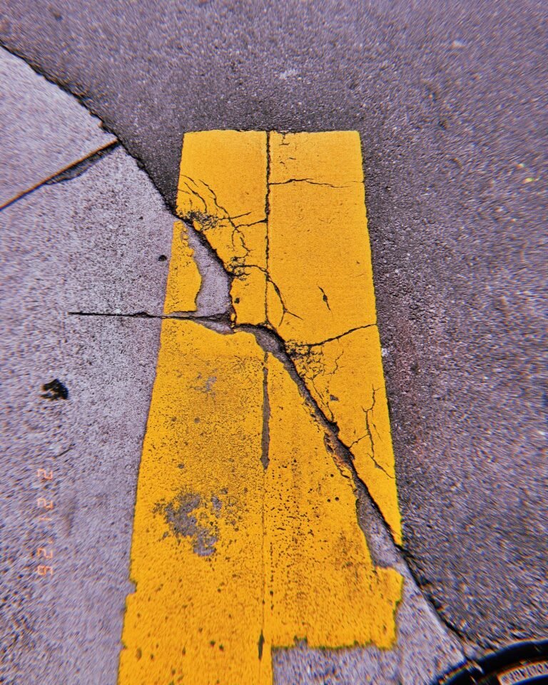cracked yellow road marking remaining on worn asphalt surface