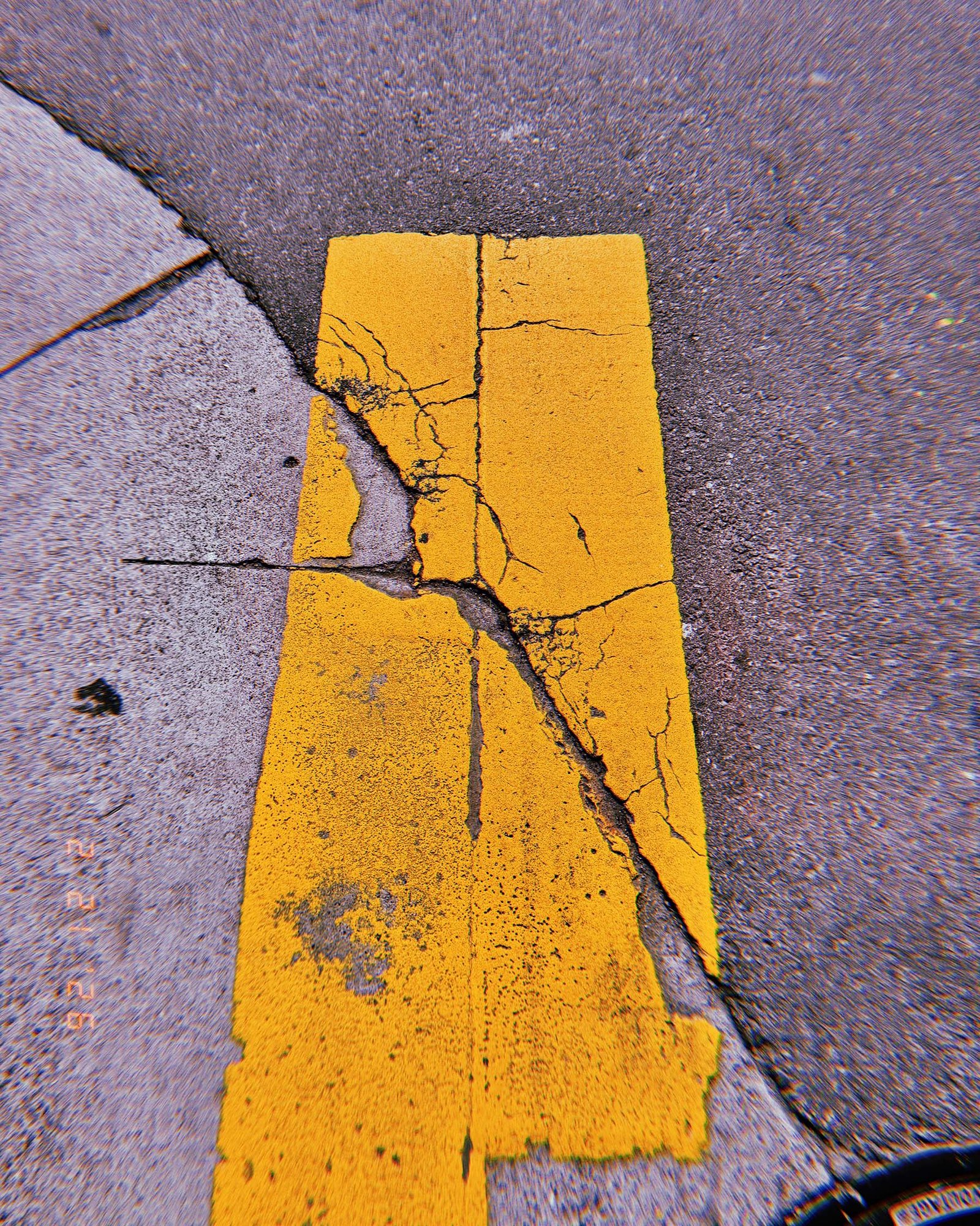cracked yellow road marking remaining on worn asphalt surface