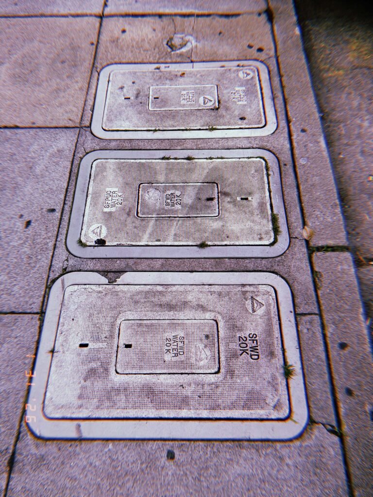 three rectangular SFWD water utility access covers embedded in sidewalk