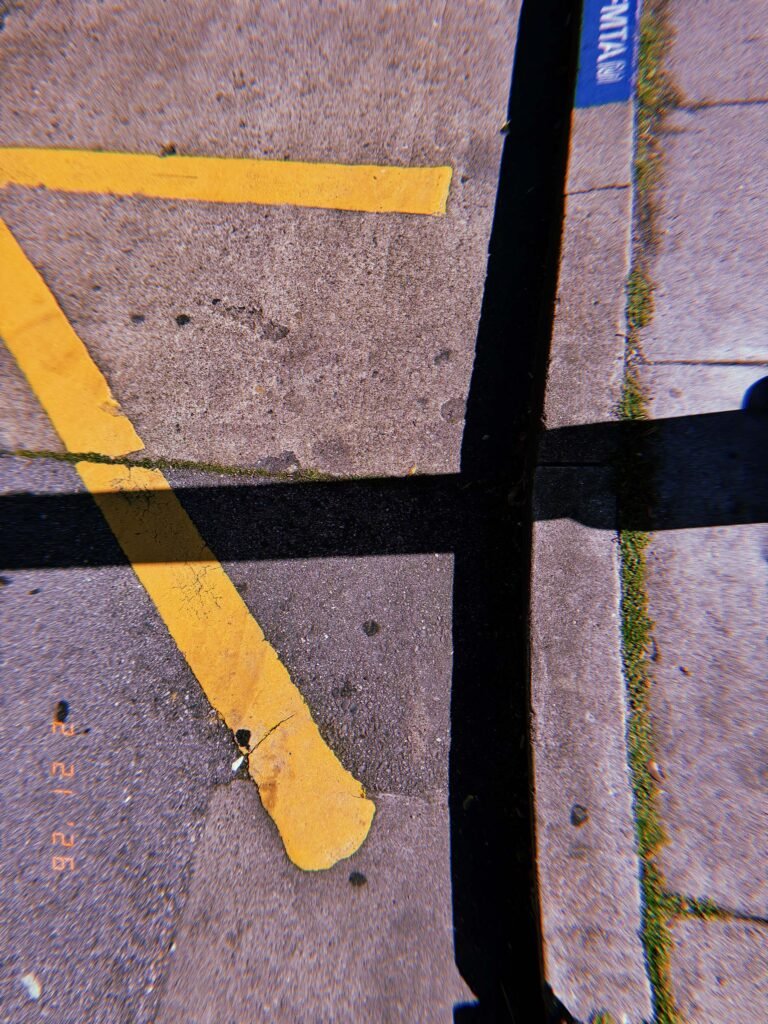 yellow pavement access marking intersected by the shadow of a street barrier