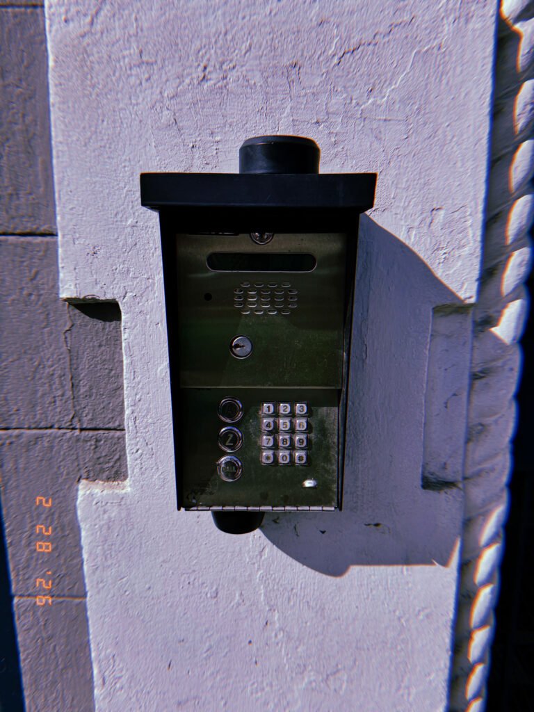wall-mounted keypad and intercom entry system protected by small metal hood
