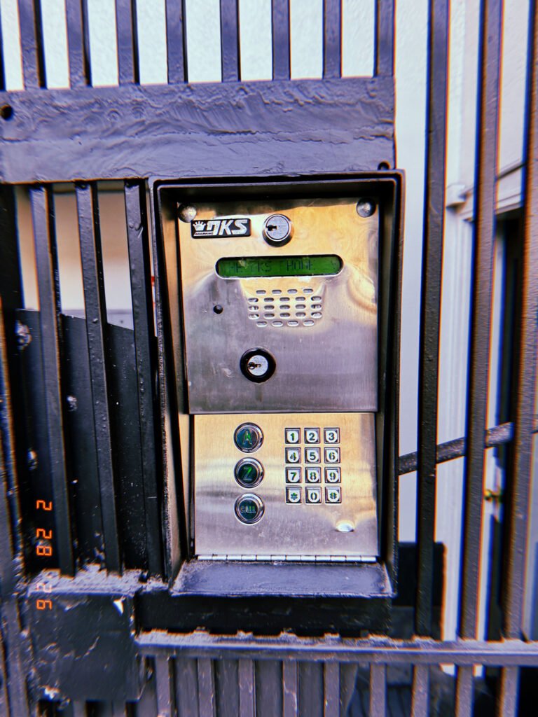 metal keypad entry and intercom unit installed in security gate frame
