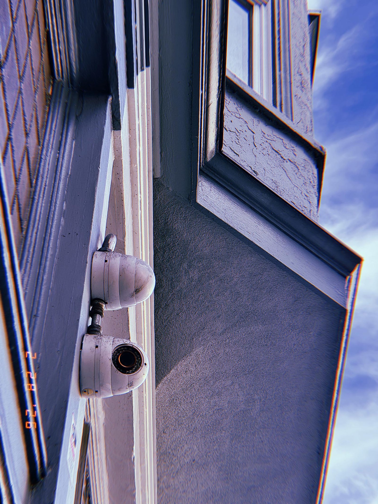 wall-mounted surveillance camera with conduit elbow joint installed near building window frame