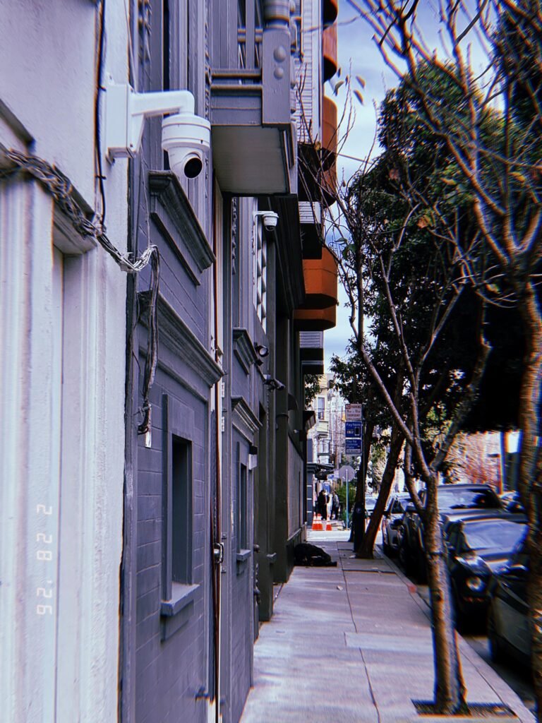 multiple surveillance cameras mounted along residential building facade overlooking sidewalk