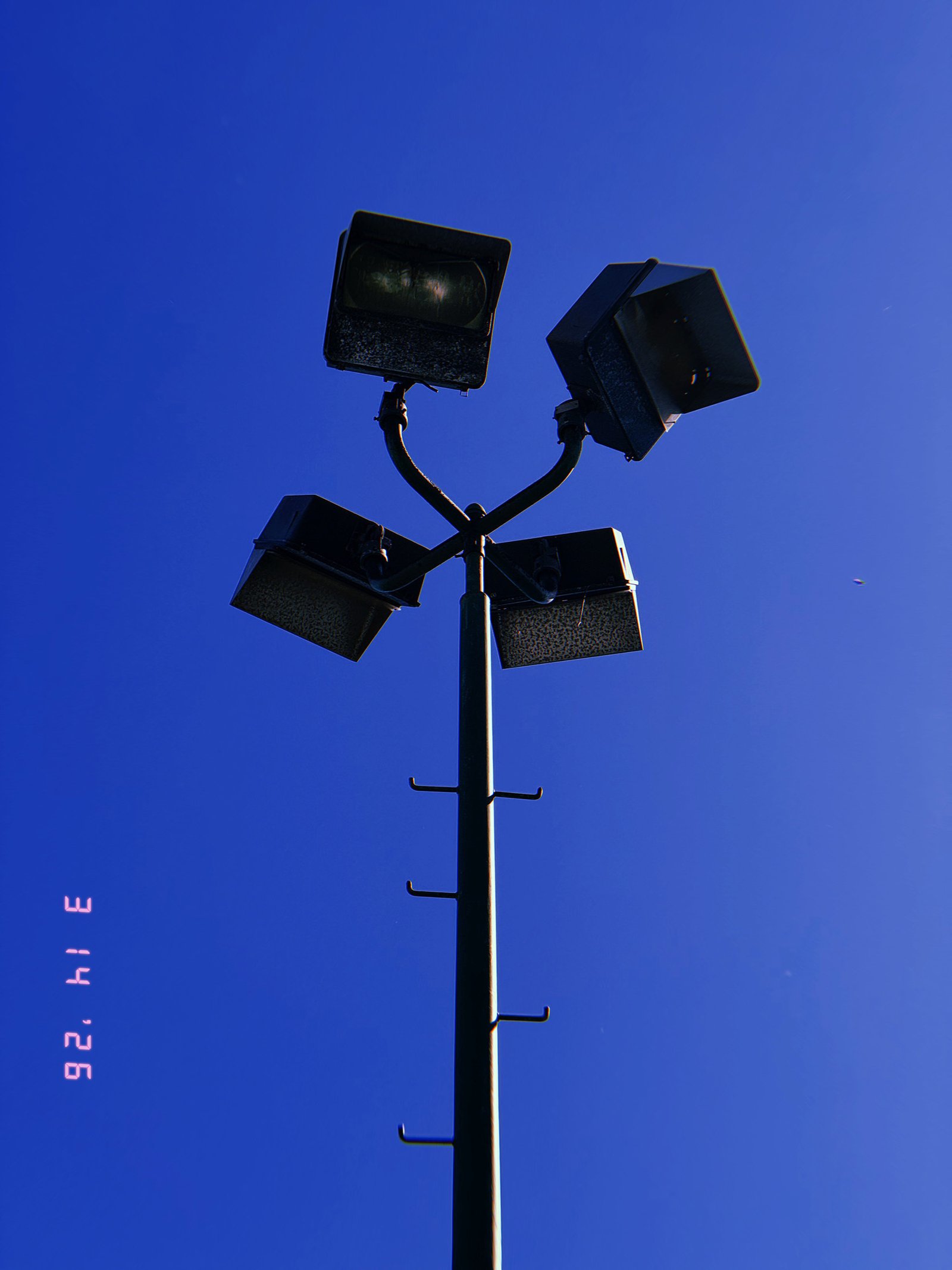 four-head floodlight array mounted on tall pole with branching arms against clear sky