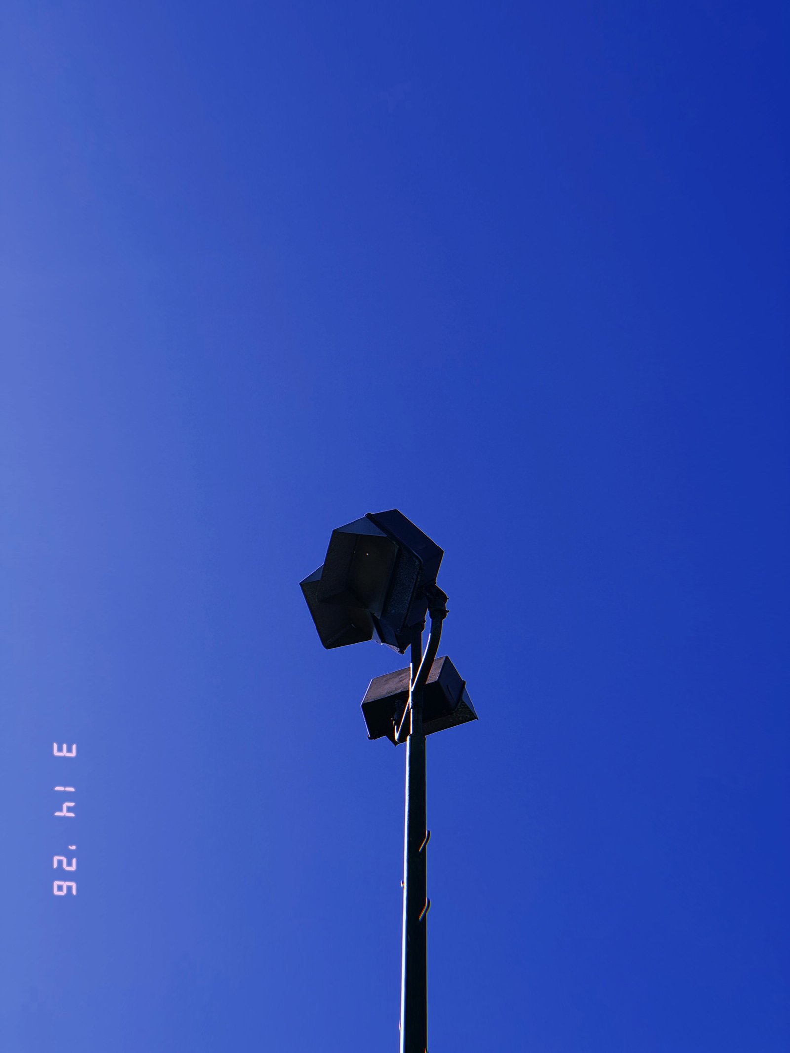cluster of rectangular floodlights mounted on tall pole against clear sky