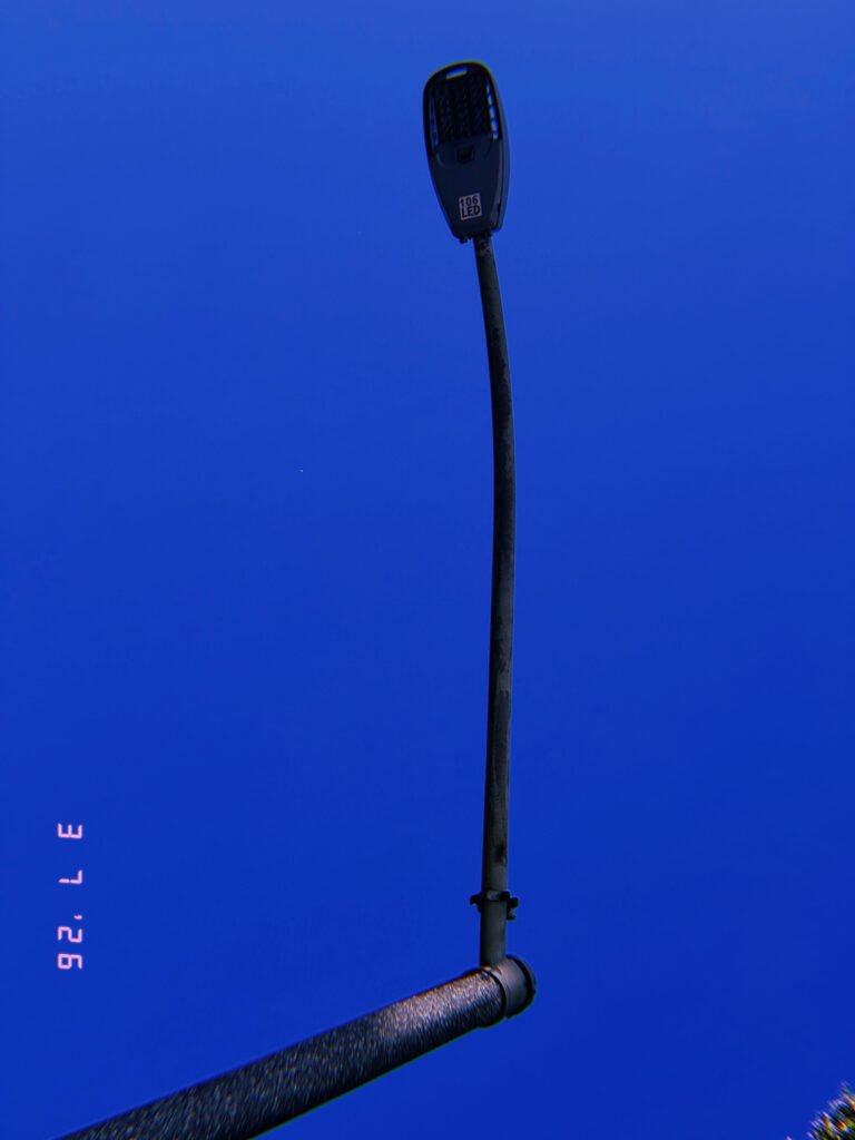 LED street light mounted on angled pole extending from horizontal support pipe against clear sky