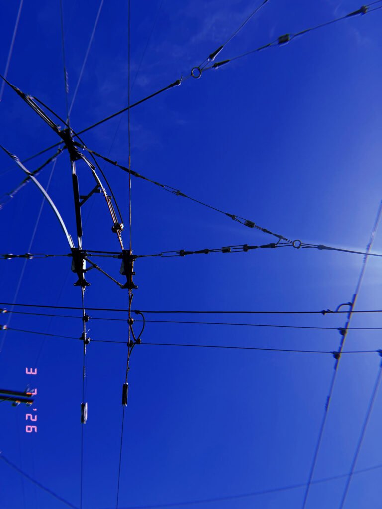 overhead transmission cables and structural supports forming radial network against blue sky