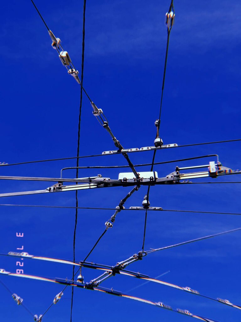 complex overhead transmission junction with multiple cables and connectors against blue sky