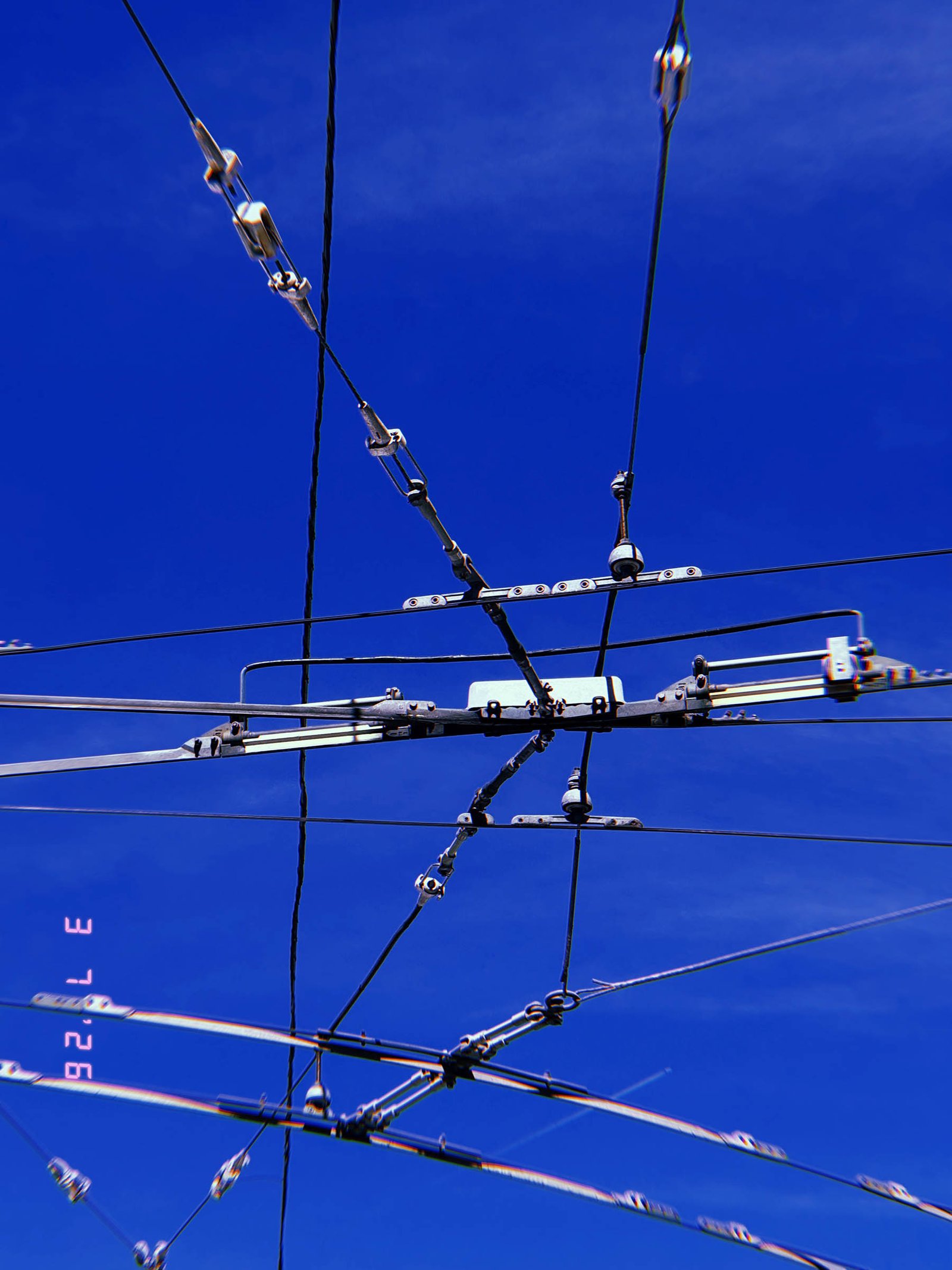 complex overhead transmission junction with multiple cables and connectors against blue sky