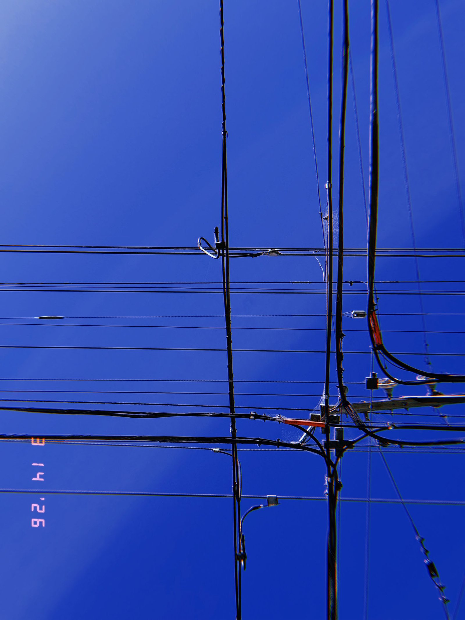 overhead utility wires forming grid-like transmission network against blue sky