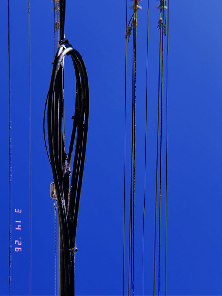 vertical utility cables and bundled transmission lines against clear blue sky