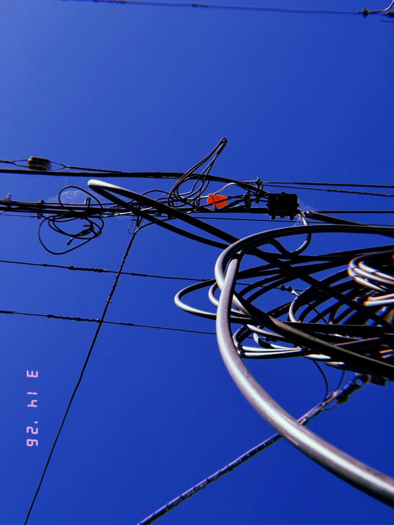 overhead utility wires and cable loops forming transmission network against blue sky