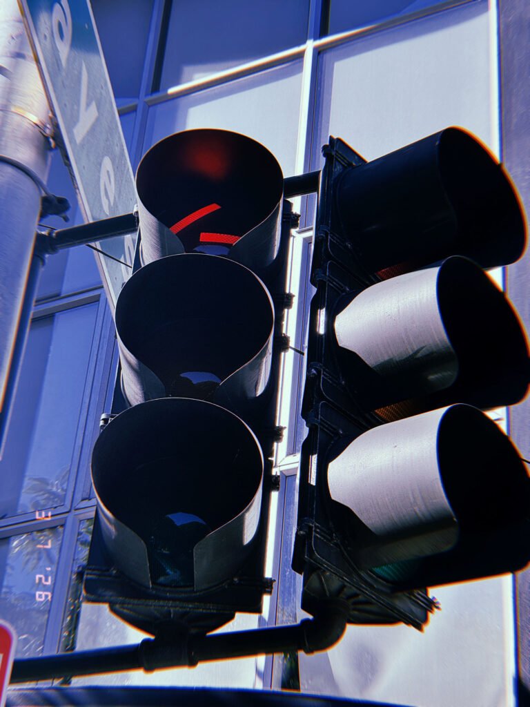 dual traffic signal units mounted on pole with red light visible against glass building facade