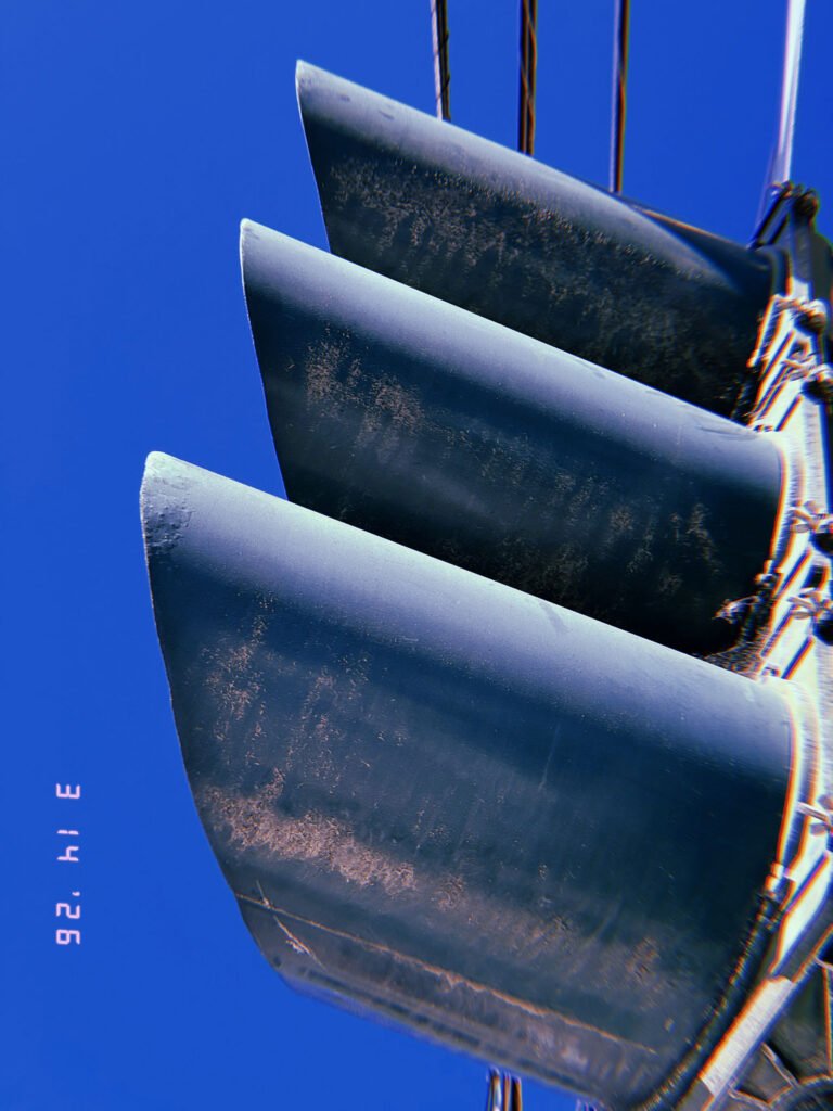 close-up of traffic signal visors aligned vertically against blue sky