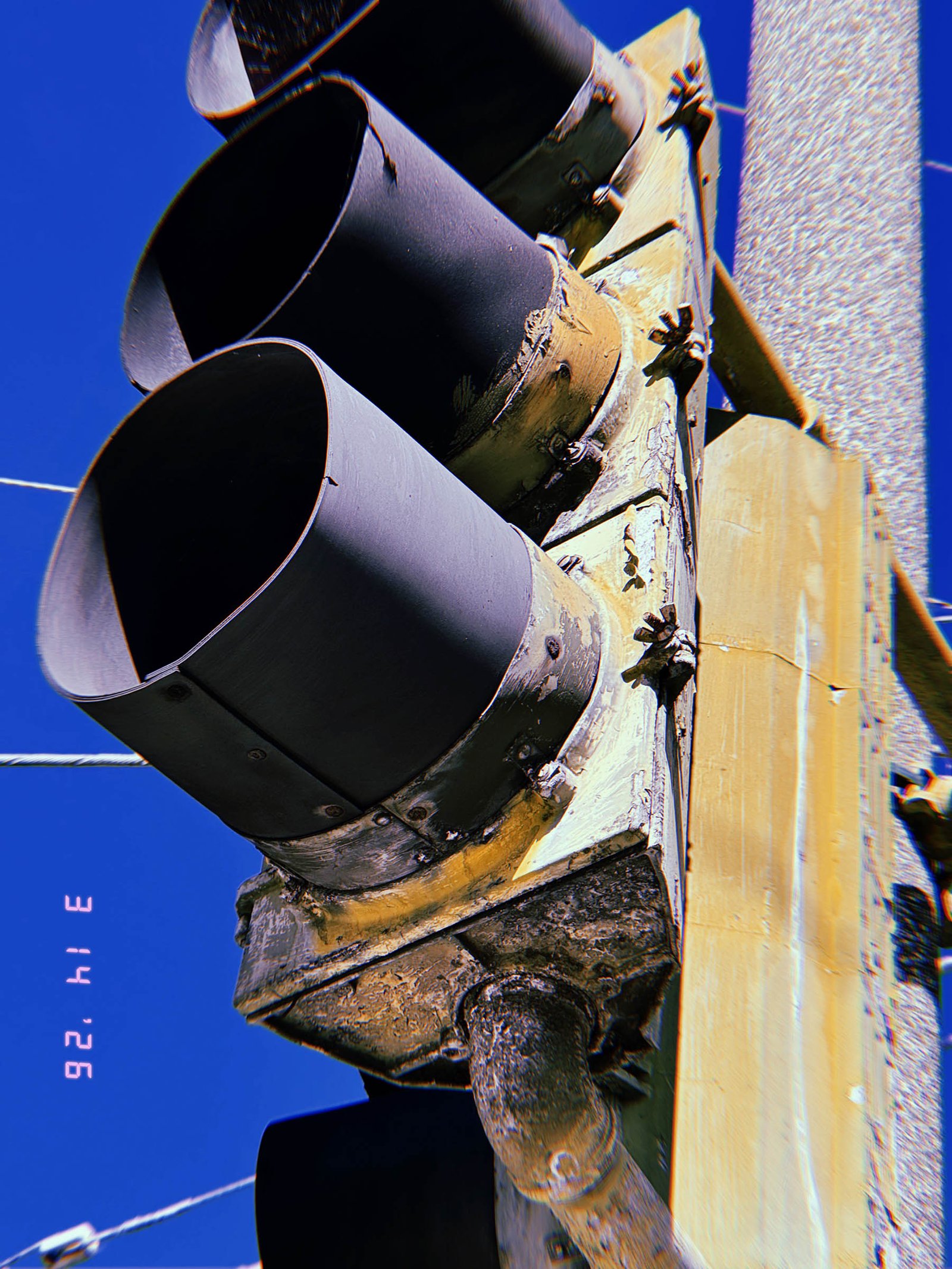 aged traffic signal lights with worn housing and hooded visors mounted on pole