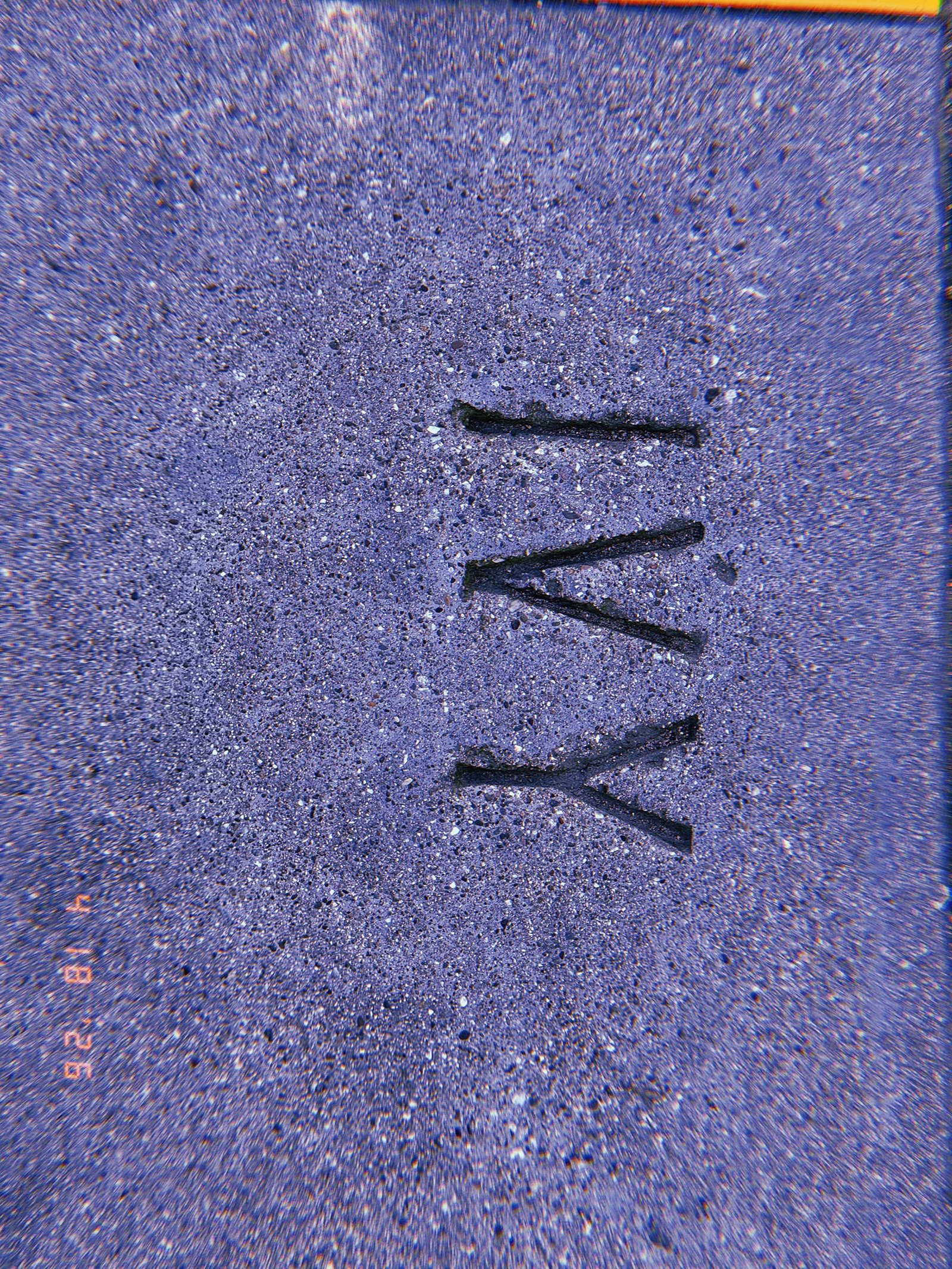 The letters “IVY” embedded into a concrete sidewalk surface, forming a permanent street identification marker surrounded by textured pavement.