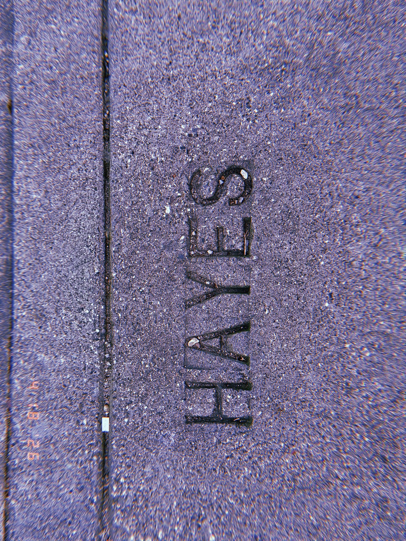 The word "HAYES" embedded in a concrete sidewalk surface as a permanent street identification marker.