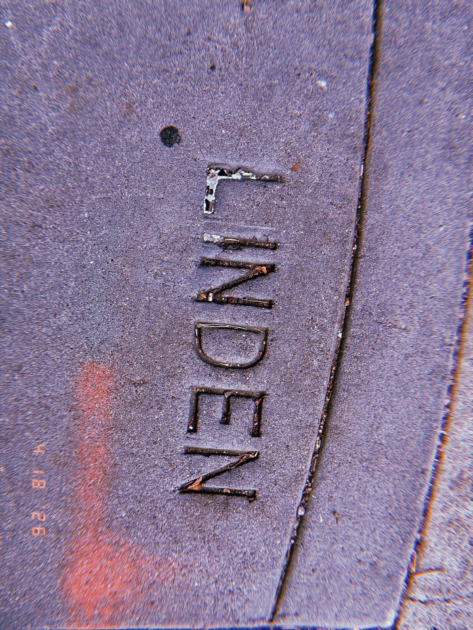 The word "LINDEN" embedded in a curved concrete sidewalk section at a street corner.