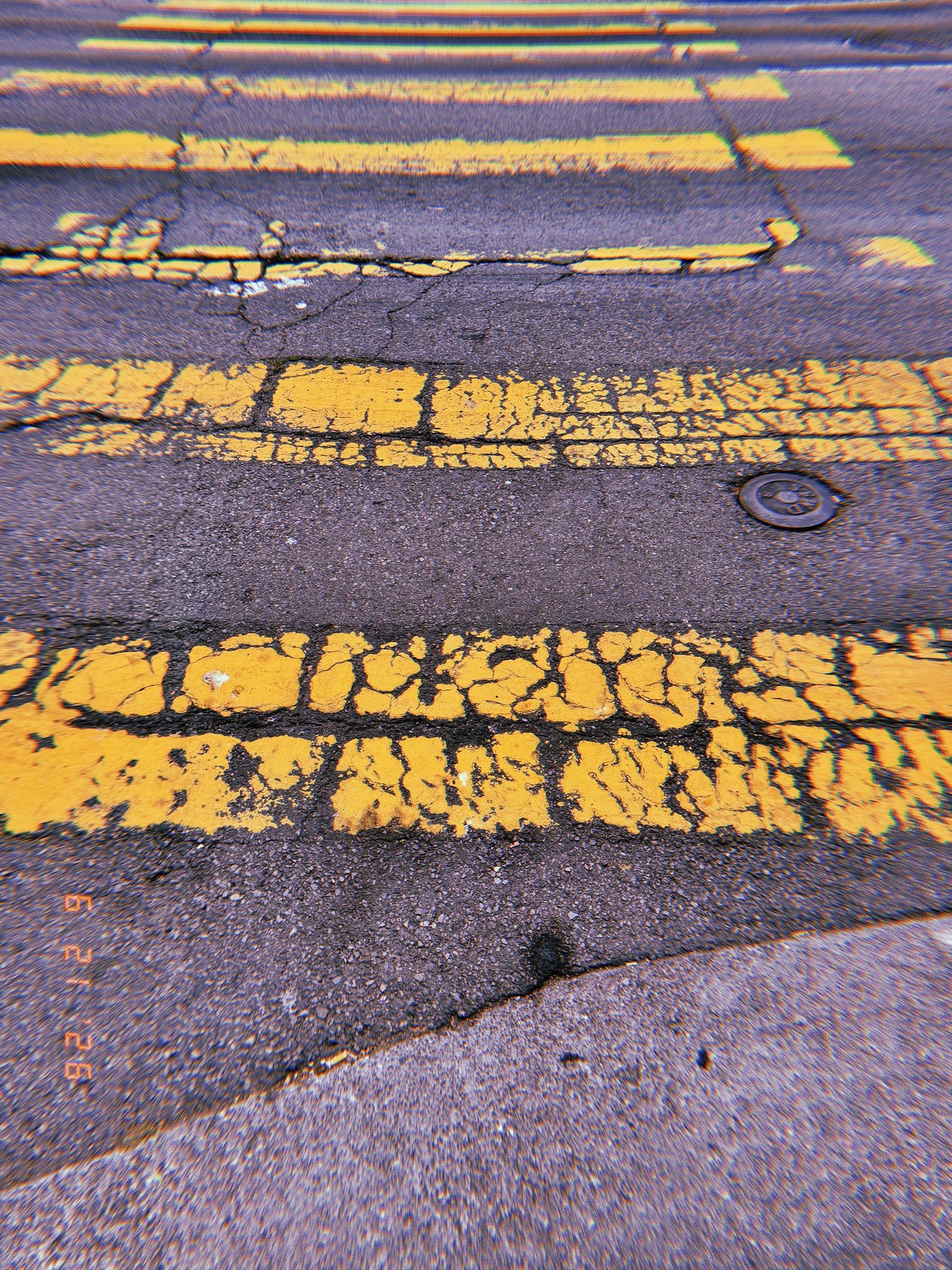 Cracked and fragmented yellow crosswalk stripes across worn asphalt in San Francisco.
