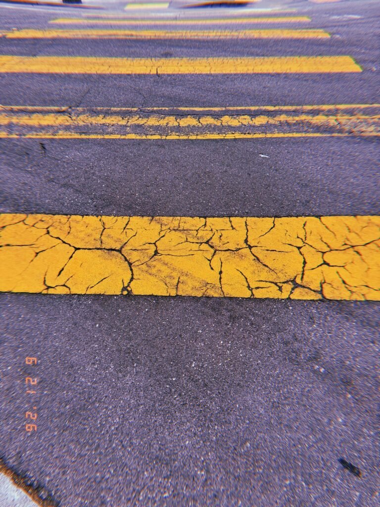 Cracked yellow crosswalk stripes repeating across dark asphalt in San Francisco.