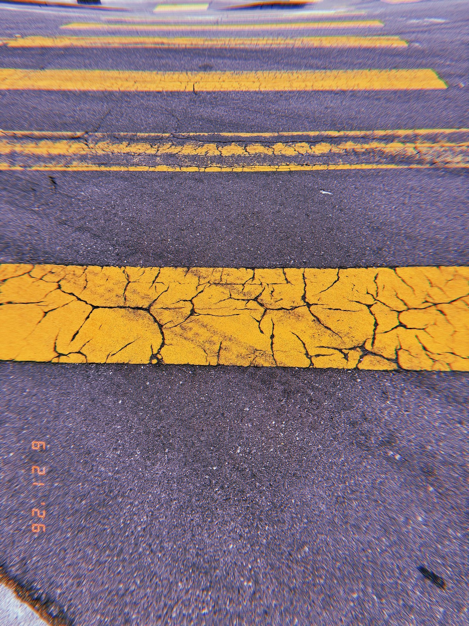 Cracked yellow crosswalk stripes repeating across dark asphalt in San Francisco.