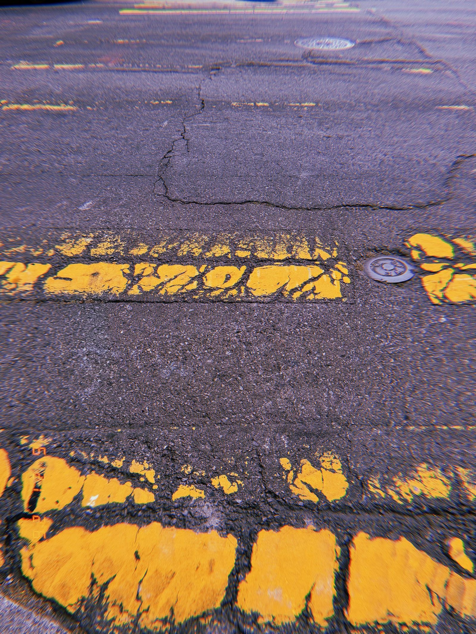 Worn yellow crosswalk markings on cracked asphalt in San Francisco.
