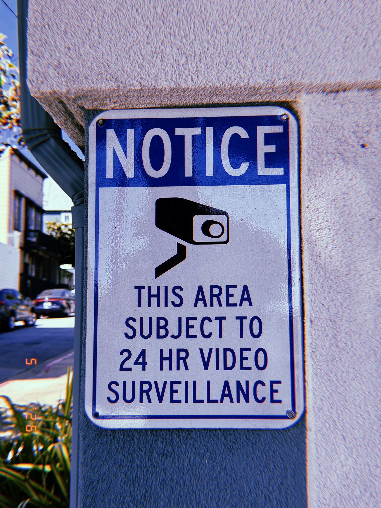Notice sign stating that the area is subject to 24-hour video surveillance, with a security camera graphic, mounted on an exterior wall in San Francisco.
