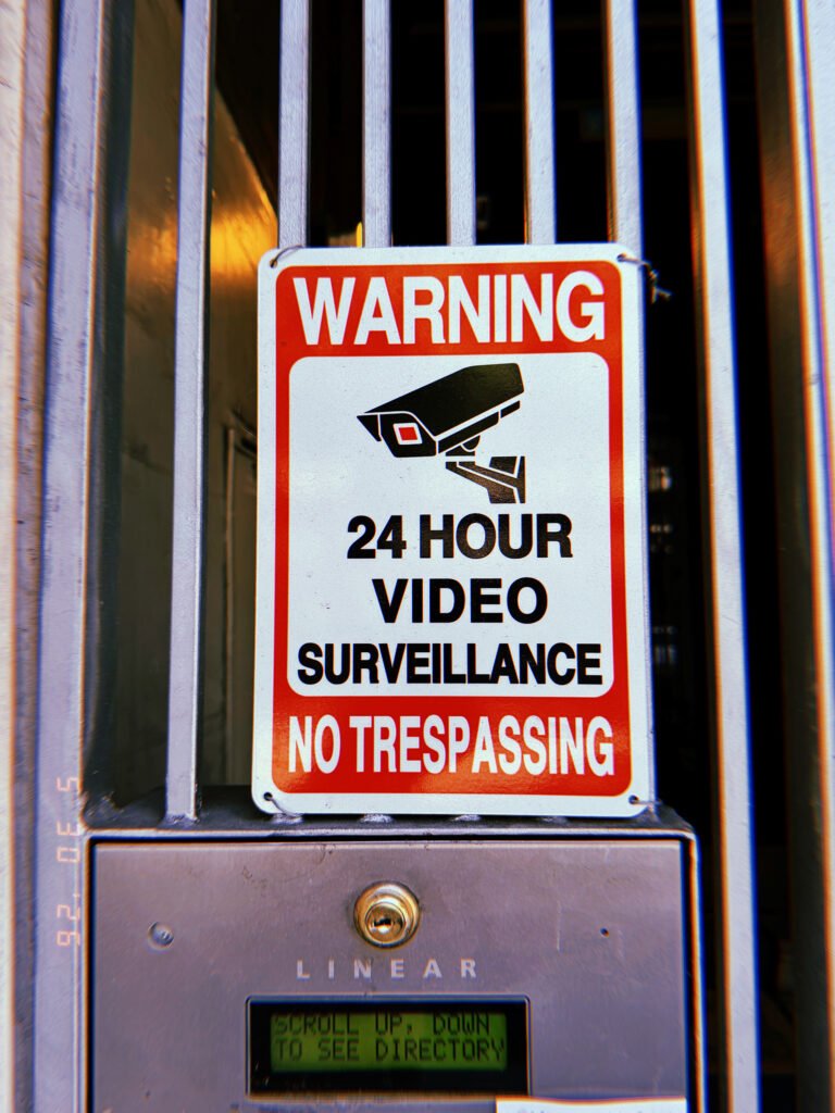 Warning sign for 24-hour video surveillance and no trespassing mounted on a gated entrance in San Francisco.