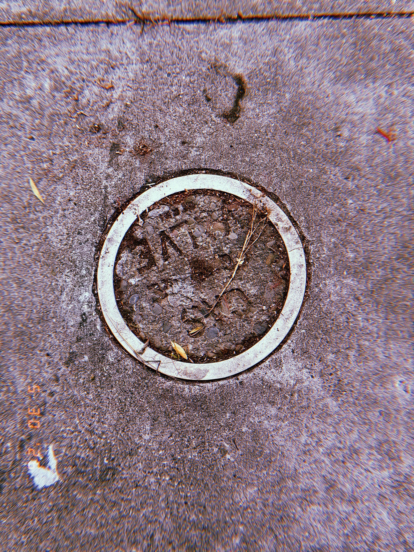 Circular gas utility access point embedded in a textured San Francisco sidewalk, filled with rough concrete and surrounded by a worn pale ring.