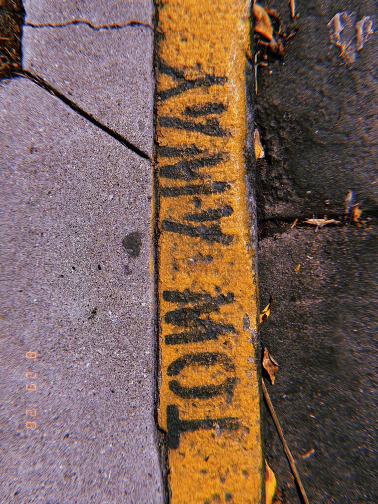 Black “COMMERCIAL LOADING” lettering painted on a worn yellow curb beside a concrete sidewalk.