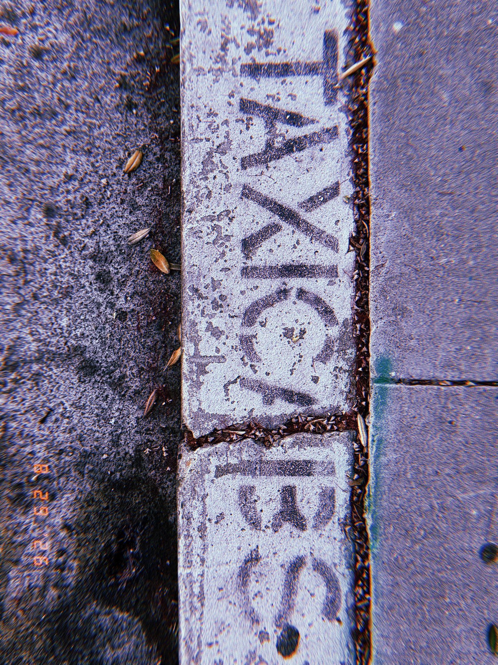 Faded black “TAXI” and “153” markings painted on a worn white curb beside a San Francisco sidewalk.