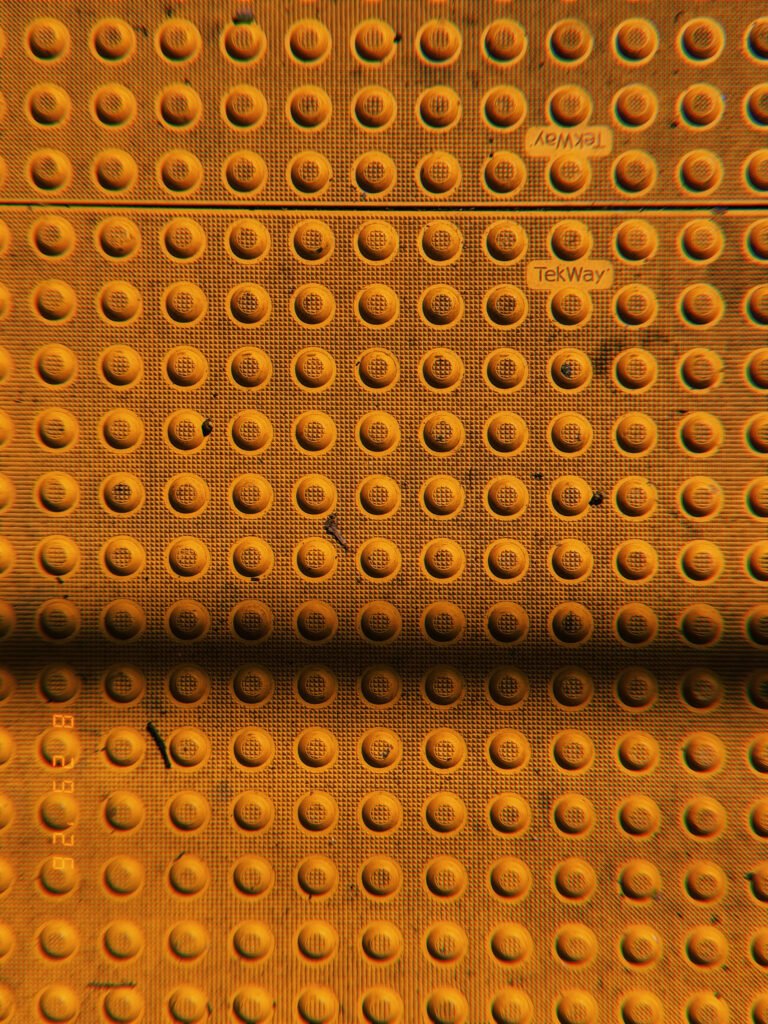 Orange tactile paving with a grid of raised truncated domes at a pedestrian curb ramp.