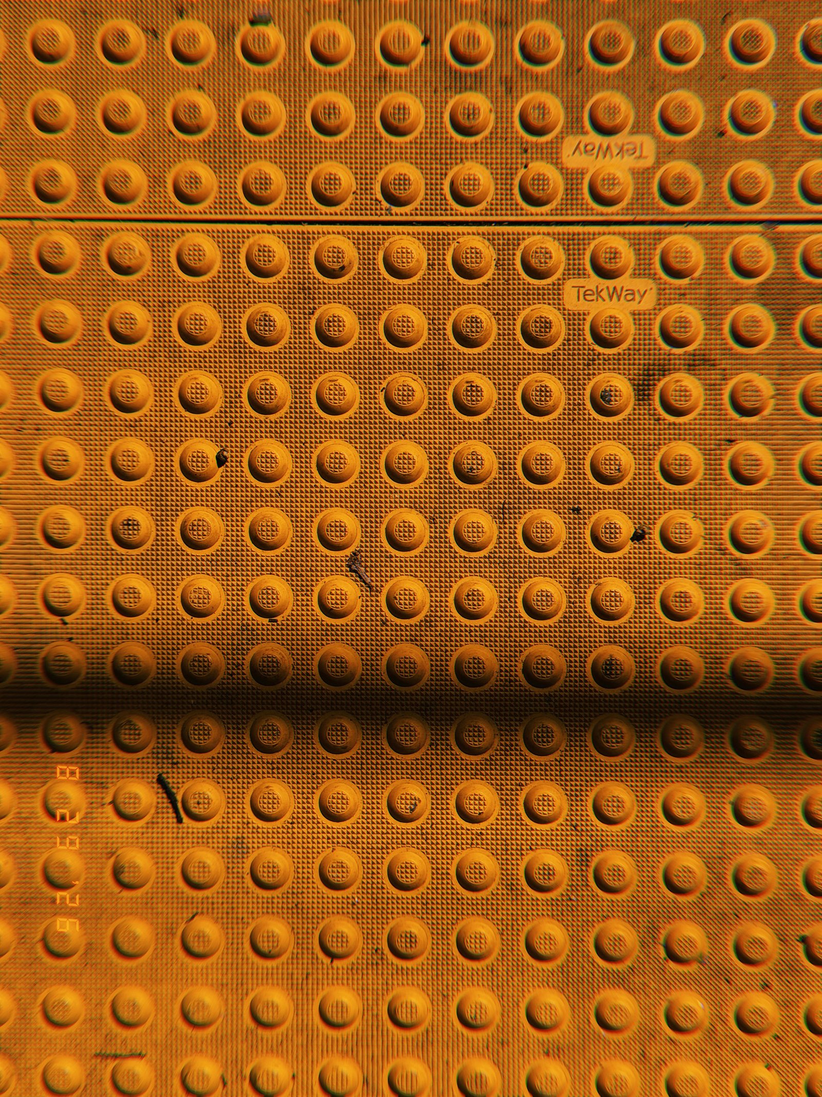 Orange tactile paving with a grid of raised truncated domes at a pedestrian curb ramp.